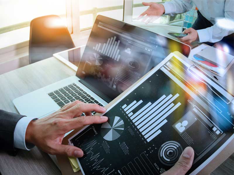 Financial services professional reviewing charts and data on a laptop for technology planning and business analysis.